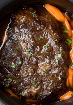 beef stew in a crock pot with carrots and parsley on the side