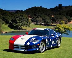 a red, white and blue sports car parked in the grass