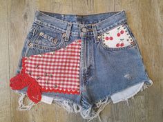 "These petite sized high waisted vintage Levi jean shorts were customised with a realy country look, reminding me of Daisy Duke and Jessica Simpson.   It features red checked ginham, vintage red crochet lace, cherries to the front pocket, with ric rac trim front and back.  Metal studs add some spunk.  So definitely one of a kind.  The vintage leather tag reads  Waist 25\" (64cm).   Measurements taken laid flat, so please double as needed. Waist-  32 cm - 12.5\" Front Rise- 27 cm - 10.5'' (From top of waist to crotch seam.) Inseam  4 cm - c. 1.5''   Length Down Front - 24 cm - 9.5\" Hips 47cm - 18.5''" Fitted Patchwork Shorts For Summer, Vintage High-waisted Jean Shorts For Spring, Retro Cutoff Jean Shorts For Spring, Retro Fitted Cutoff Shorts, Vintage Jean Shorts For Spring, Vintage Style Jean Shorts For Spring, Retro Fitted Denim Shorts, Retro Reworked Jeans For Summer, Fitted Retro Denim Shorts