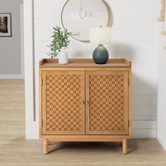 a wooden cabinet with a plant on top and a round mirror hanging above the door