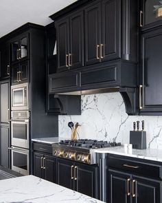 a kitchen with black cabinets and marble counter tops