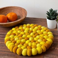 a wooden bowl with two oranges on it next to a yellow and red rug