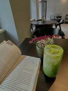 an open book sitting on top of a table next to a glass filled with liquid