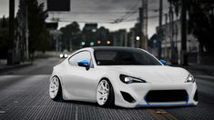 a white sports car with blue accents on the front parked in an empty street at night