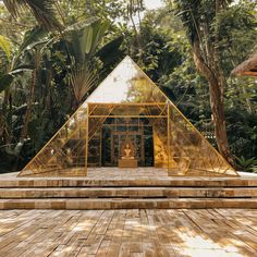 a pyramid shaped structure in the middle of a wooden deck surrounded by trees and plants