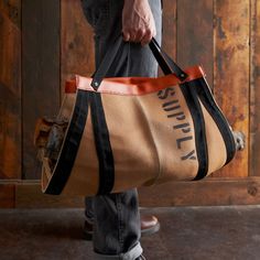 a person holding a brown and black duffel bag