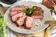 a white plate topped with sliced up meat and garnished with parmesan