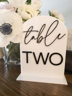 there is a sign that says table two with flowers in the vase on the table