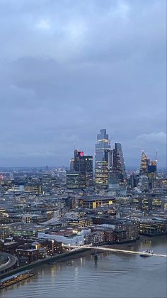 an aerial view of the london skyline at night with boats in the water and skyscrapers lit up