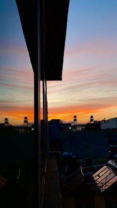 the sun is setting over some buildings and rooftops in this view from an outside patio