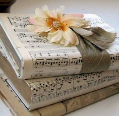 three books are stacked on top of each other with sheet music notes and a flower