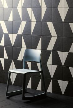 a white chair sitting in front of a black and white wall with triangles on it