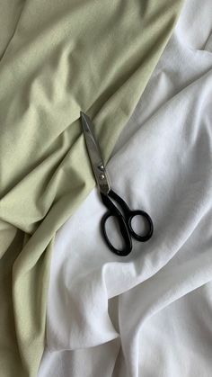 a pair of scissors sitting on top of a white sheet covered in sheets and fabric