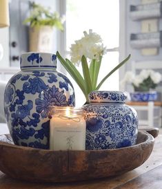 a blue and white vase sitting on top of a wooden table next to a candle