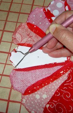 a person cutting fabric with a pair of scissors on top of the material that is being sewn together