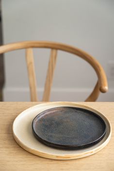 a black and white plate sitting on top of a wooden table next to a chair