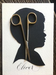 a pair of scissors cut into the shape of a woman's head on top of a piece of paper