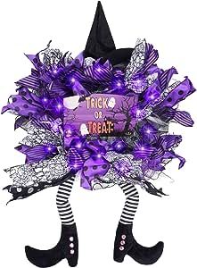 a halloween wreath with purple flowers and black stockings on the legs, holding a trick or treat sign