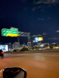 a car driving down the road in front of a large cityscape at night