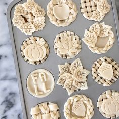 twelve decorated cookies sitting on top of a cookie sheet in the shape of pies