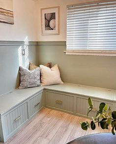 a window seat with pillows on it next to a table