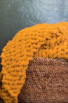 a large yellow blanket sitting on top of a wicker basket next to a wall