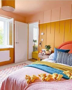 a bedroom with yellow walls and orange bedding on the floor, along with two pillows