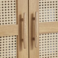 two wooden handles on a door with perforated screen in the backround