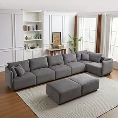 a large gray sectional couch sitting on top of a wooden floor next to a window