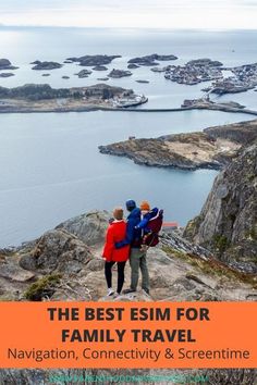 two people standing on top of a mountain looking out at the water and land below