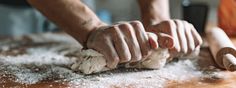 a person kneading dough on top of a wooden table