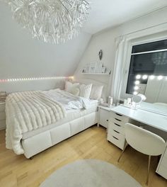 a bedroom with white furniture and a chandelier hanging from the ceiling