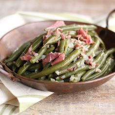 a wooden bowl filled with green beans covered in bacon