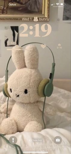 a white stuffed animal with headphones on top of a bed next to a painting