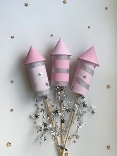 three pink and silver party hats on top of sticks with stars in the sky around them