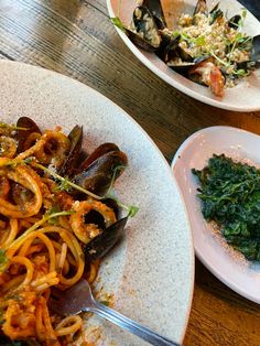 pasta with mussels and greens on a white plate