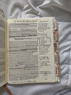 an open bible on a bed with white sheets