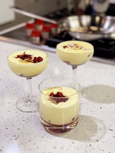 three glasses filled with dessert sitting on top of a counter