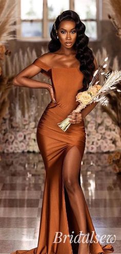 a woman in an orange dress holding flowers and posing for the camera with her hands on her hips