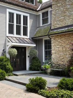 a gray house with white trim and stone steps leading up to the front door area