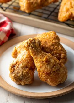 three fried chicken nuggets on a plate next to a cooling rack with more in the background