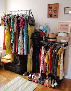 a closet filled with clothes and shoes next to a wall mounted rack full of scarves