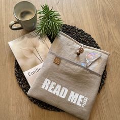 a coffee cup and some books on a table with a plant in the middle of it