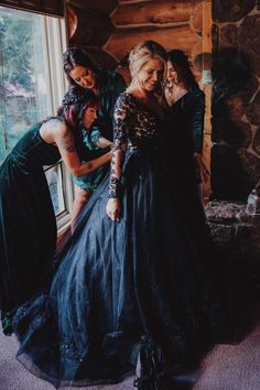 three women in long dresses standing by a window