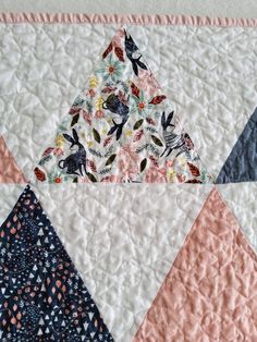 a quilted wall hanging with several different colored triangles on it's sides and one triangle in the middle