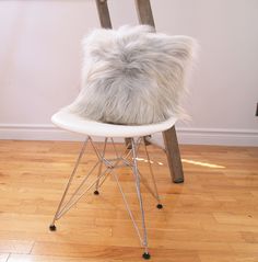 a white chair with a furry seat cushion on it's back in front of a wooden ladder