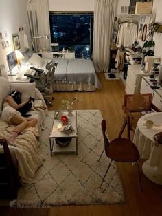 a woman sitting on a couch in a living room next to a bed and table