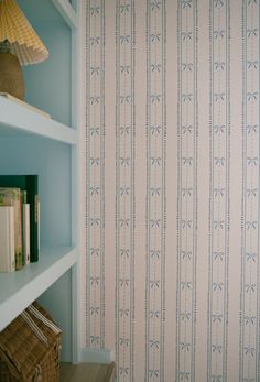 a book shelf in front of a wallpapered room with blue walls and shelves