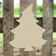 a wooden cutout of a white christmas tree on a fence in front of a field