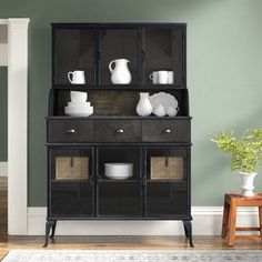 a black china cabinet with glass doors and baskets on the bottom shelf next to it